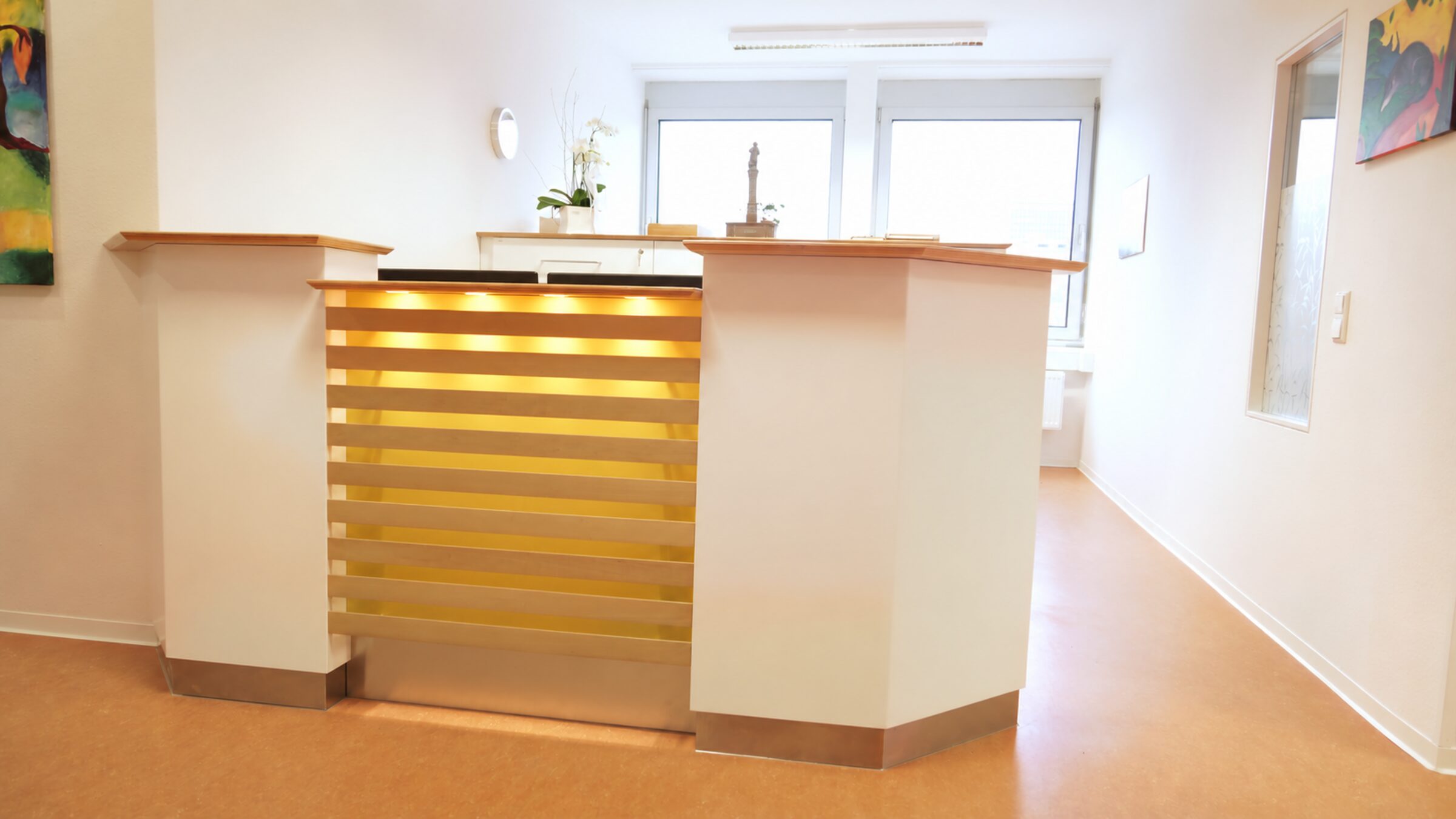Empfangstresen der Praxis mit warm beleuchteten Holzlamellen